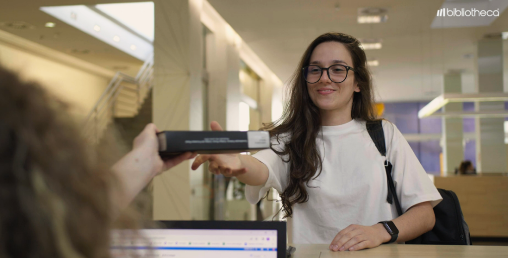 Estudante recebendo seu livro na Biblioteca Univates