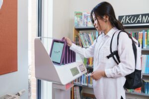 Acesso estendido 2 Pessoa utilizando um Hublet para empréstimo de tablet em biblioteca, promovendo autoatendimento e acesso à tecnologia para os usuários.