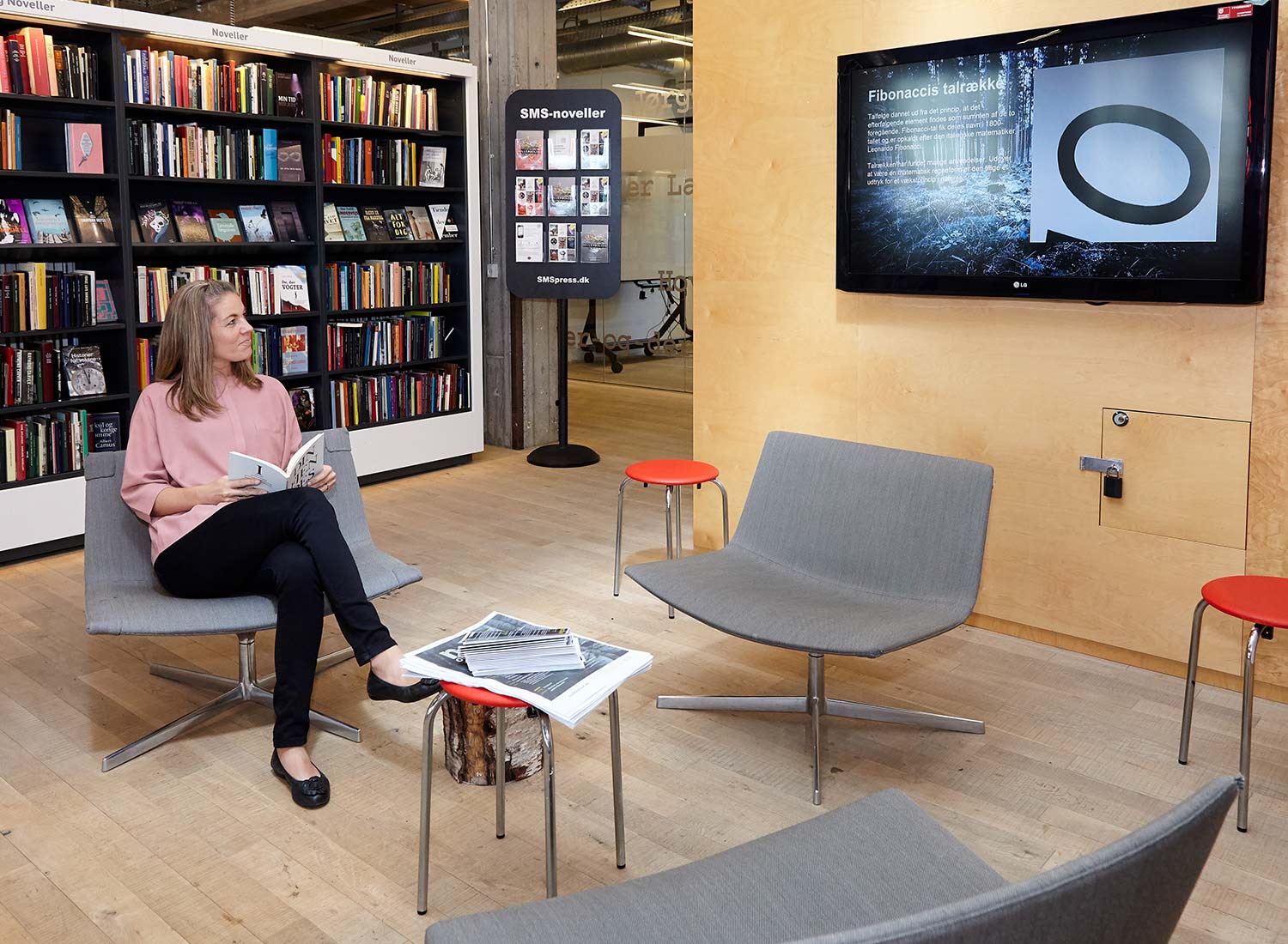 Frau sieht in einer Bibliothek auf einen digitalen Bildschirm