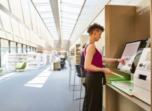 Femme utilisant la borne selfCheck 1000D à la bibliothèque de l’Université de Vienne