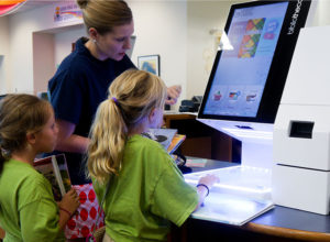 cloudLibrary app release updates 2 Mother and children checking out books at selfCheck1000D at Auburn Public Library