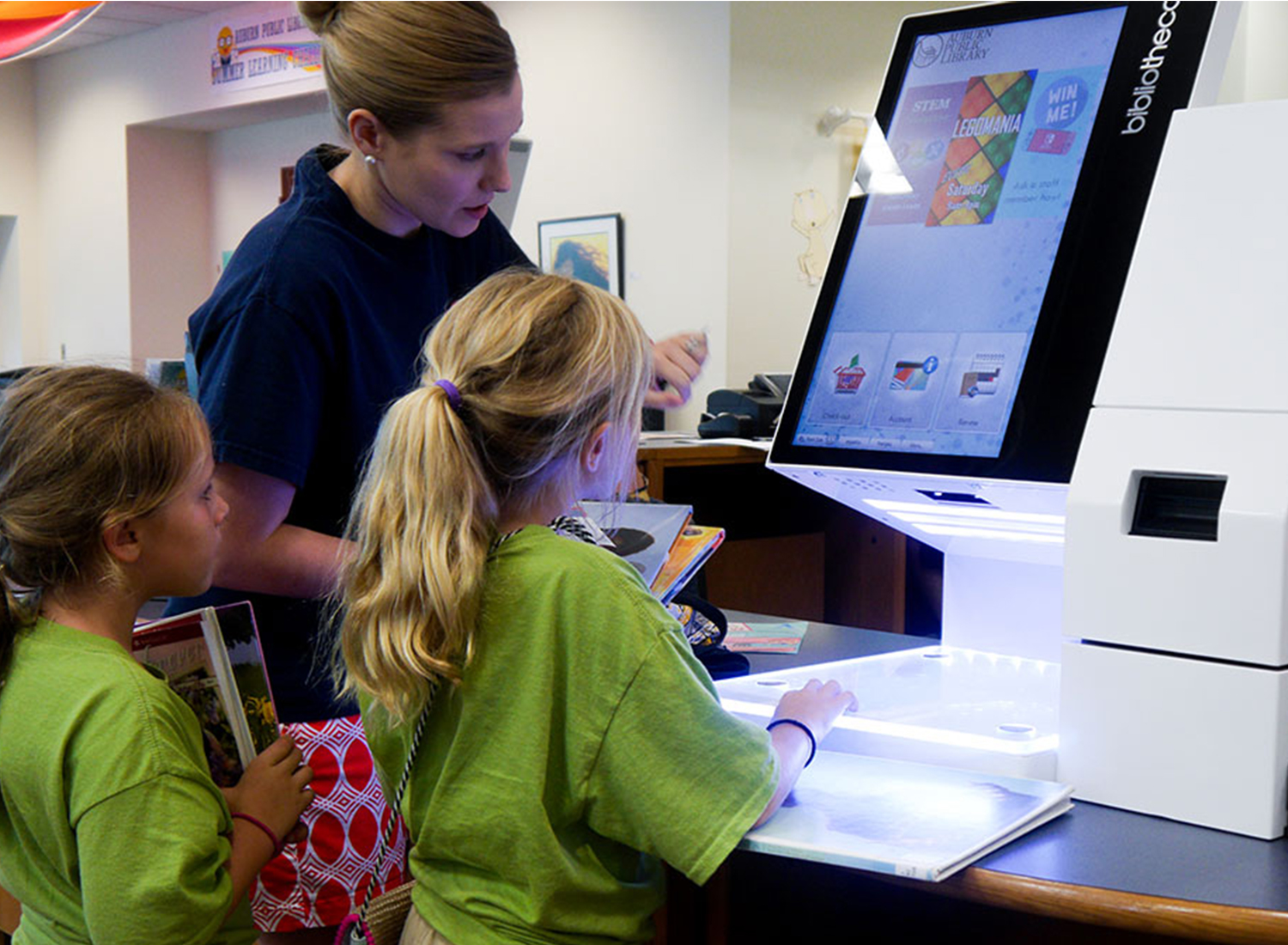 Mother and children checking out books at selfCheck1000D at Auburn Public Library