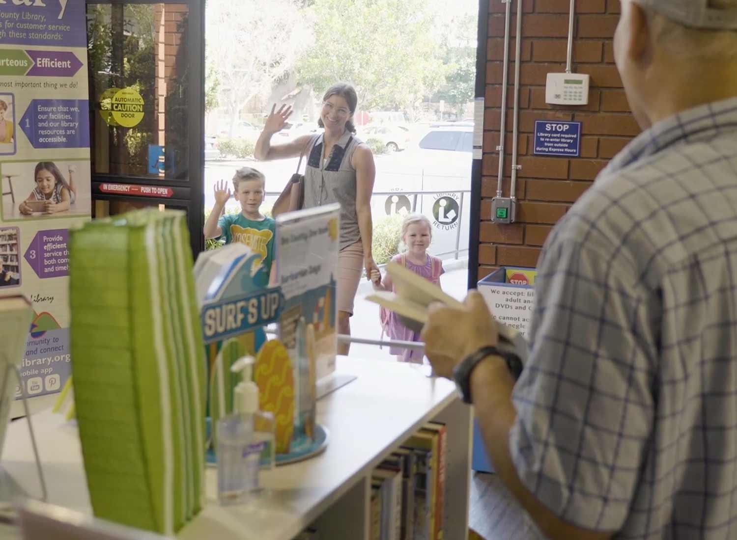 Mother and chrildren waving at librarian from library door