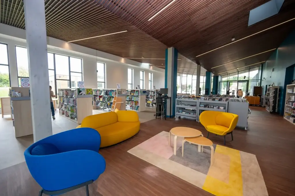 Intérieur moderne de la bibliothèque de Saint-Quentin-en-Yvelines avec espaces ouverts, rayonnages accessibles et aménagement adapté à une gestion RFID des collections.