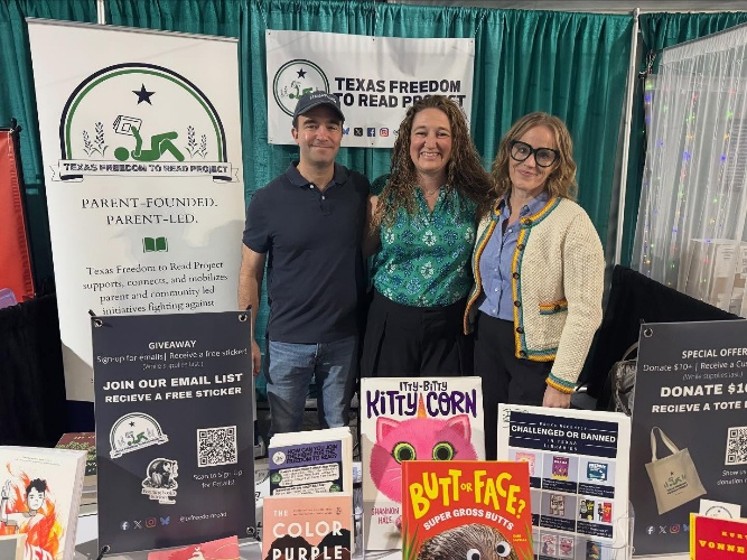 Three Texas Freedom to Read Project representatives standing behind an outreach booth with books and advocacy materials.