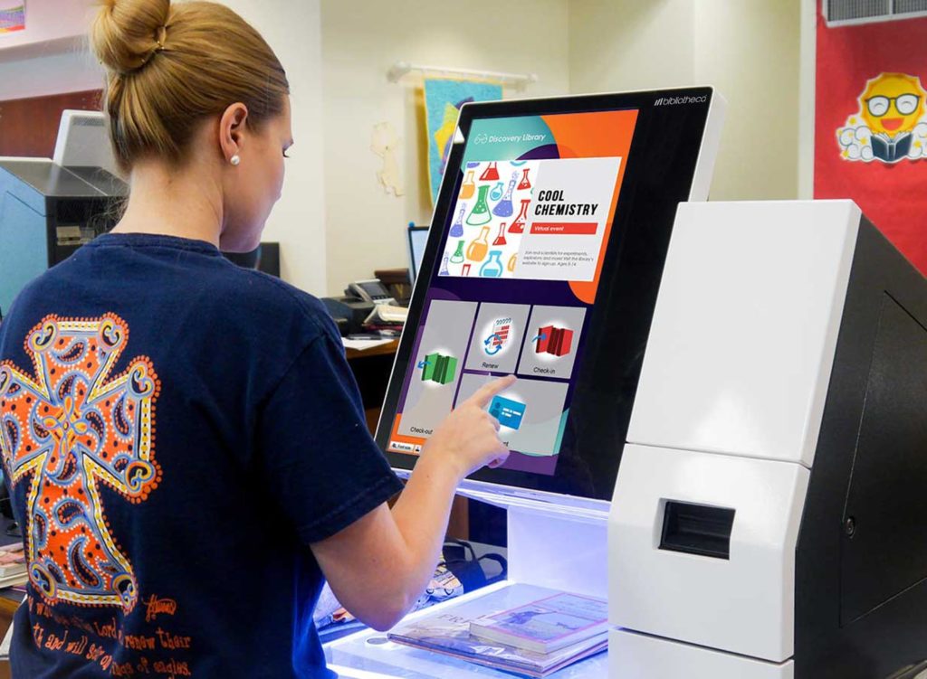 Woman uses self service checkout software and kiosk