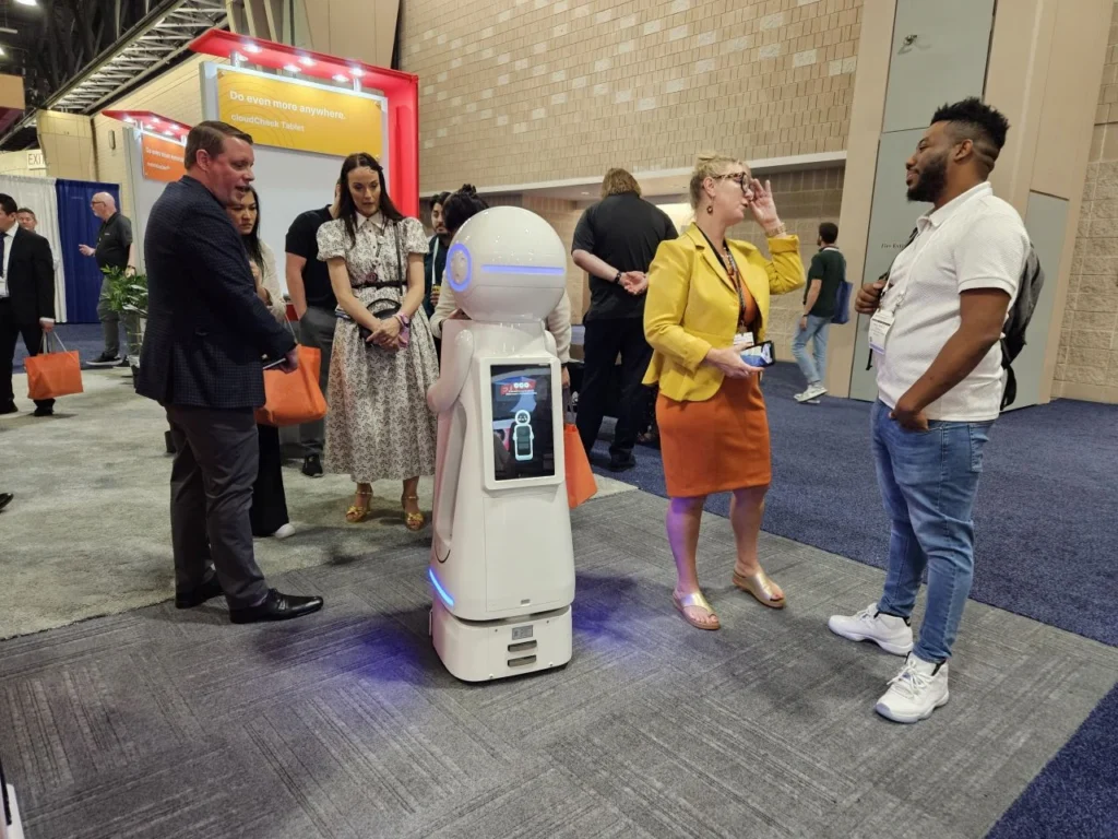 Visitors interact with Romi the robot at Bibliotheca’s booth during ALA 2025
