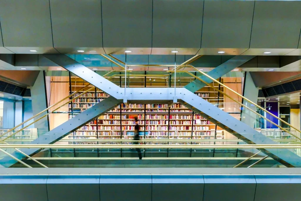 Modern library interior with bookshelves and architectural walkways, representing RFID integration and streamlined library workflows between Bibliotheca and Koha.