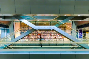 Modern library interior with bookshelves and architectural walkways, representing RFID integration and streamlined library workflows between Bibliotheca and Koha.