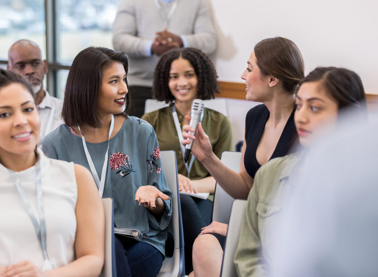 Frauen stellen bei einer Veranstaltung Fragen mit einem Mikrofon