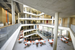 elevated view of atrium of large modern concrete college building showing balcony, mezzanine and different storeys.