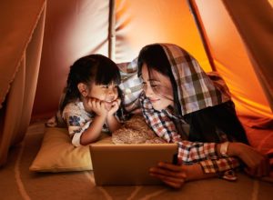 mother and daugther reading of tablet in a den