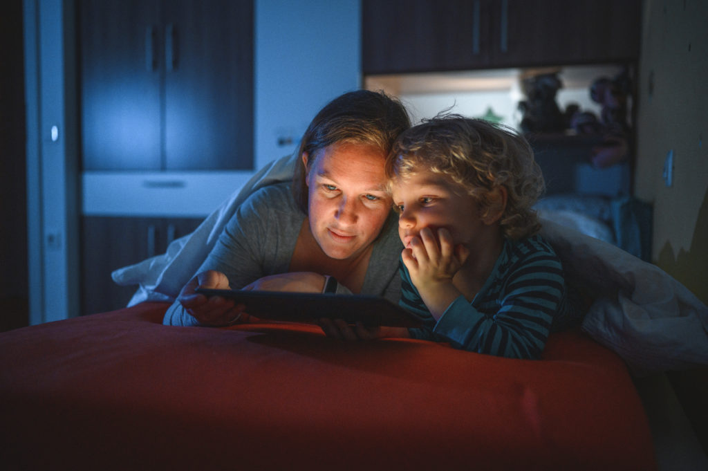 boy and his mother using digital tablet at bedtime