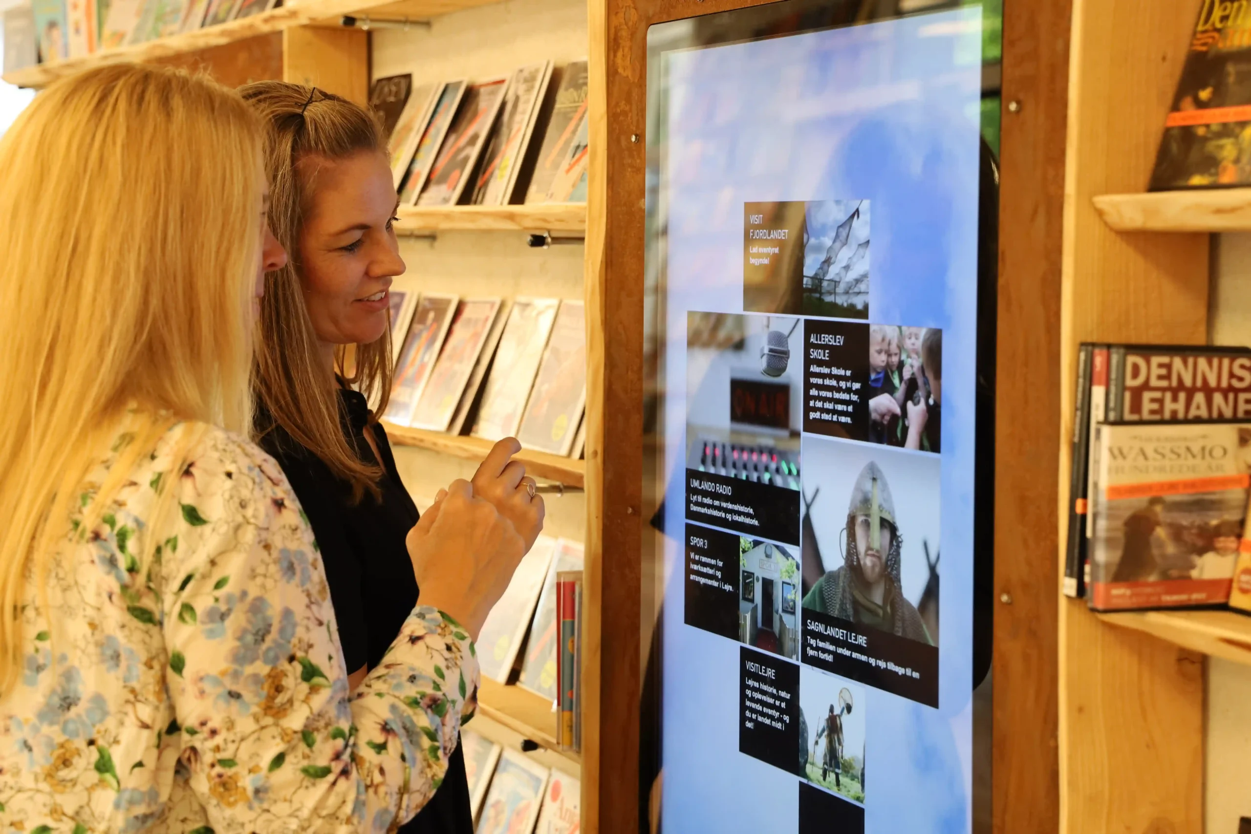 Webinar: Classics Revisited – A Theory of Justice by John Rawls 9 Two women interacting with a large digital screen displaying library content at a public library.