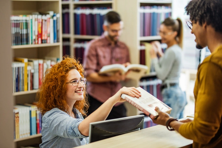 Webinar: Uplifting our Community Voices 4 Library staff member handing a book to a patron at the service desk